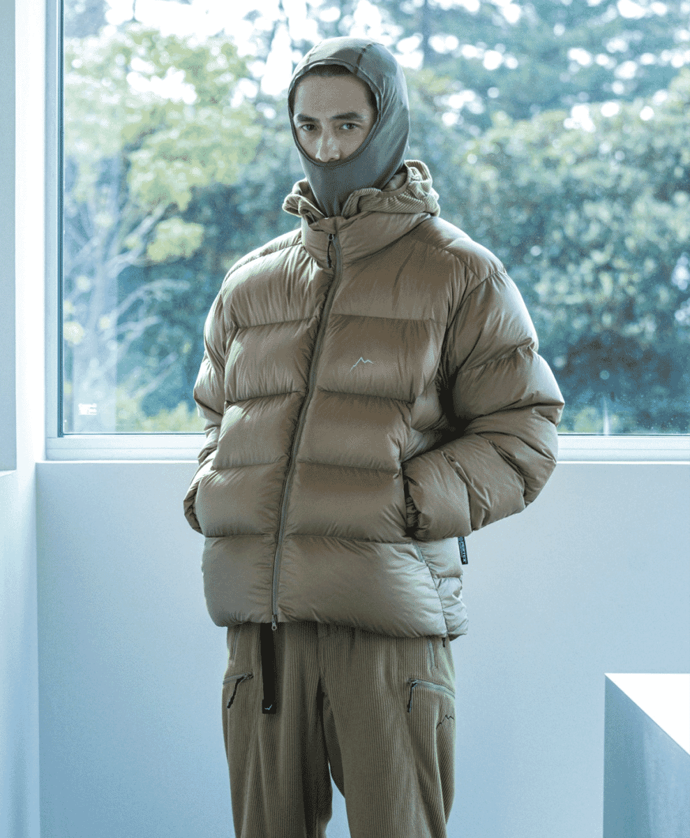 A man wearing a taupe puffer jacket and matching corduroy pants