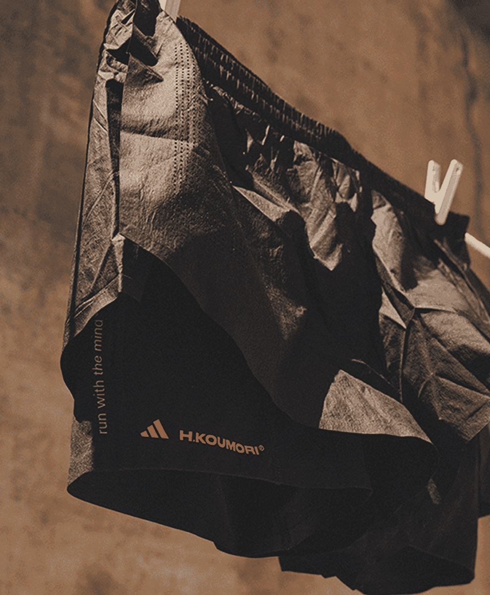Black running shorts with collaborative branding hanging on a line.