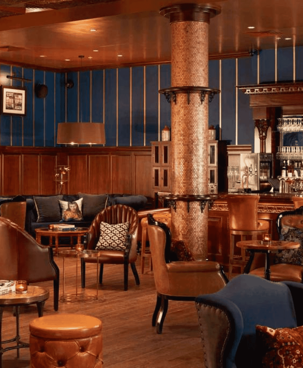 An elegant lounge with vintage leather chairs and a copper-tiled column.