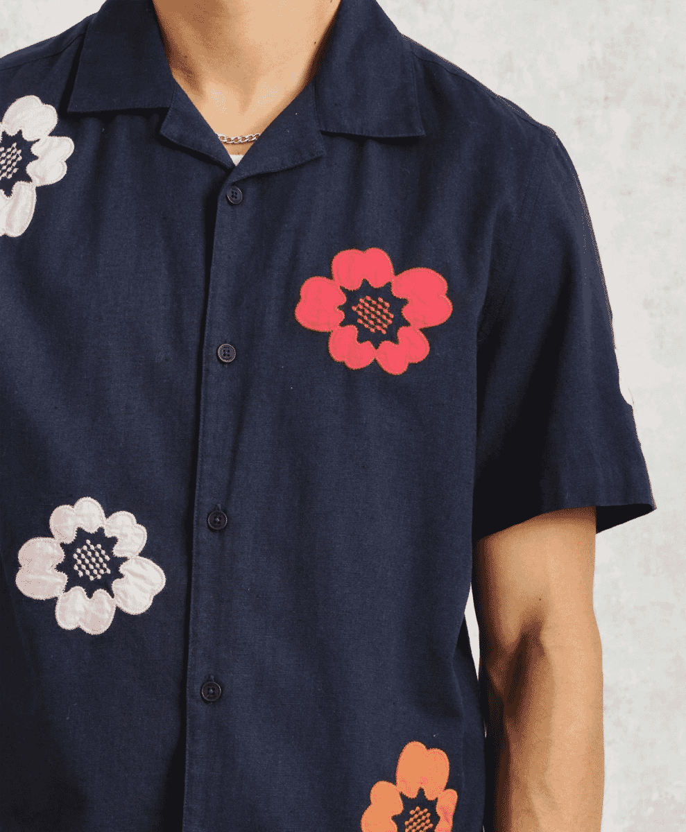 Close-up detail of red, white, and orange floral appliqués on a navy fabric.