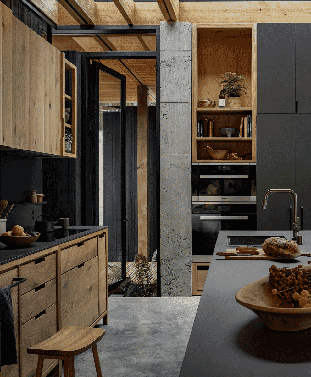 Modern kitchen with natural wood cabinetry and concrete counters in a minimalist home.