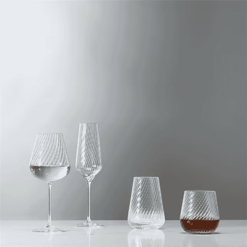 A set of modern glassware including tumblers with twisted patterns and liquid inside.
