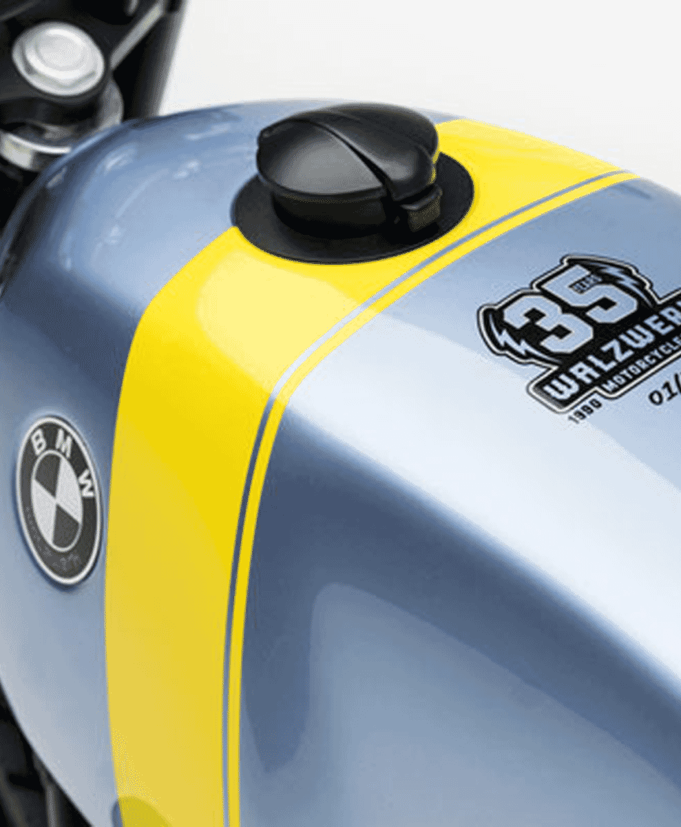 Close-up of a light blue motorcycle fuel tank with a yellow racing stripe and 35th Anniversary WalzWerk logo.
