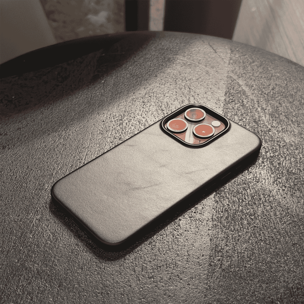 A black leather-textured phone case with a triple-camera module cutout on a gray surface.