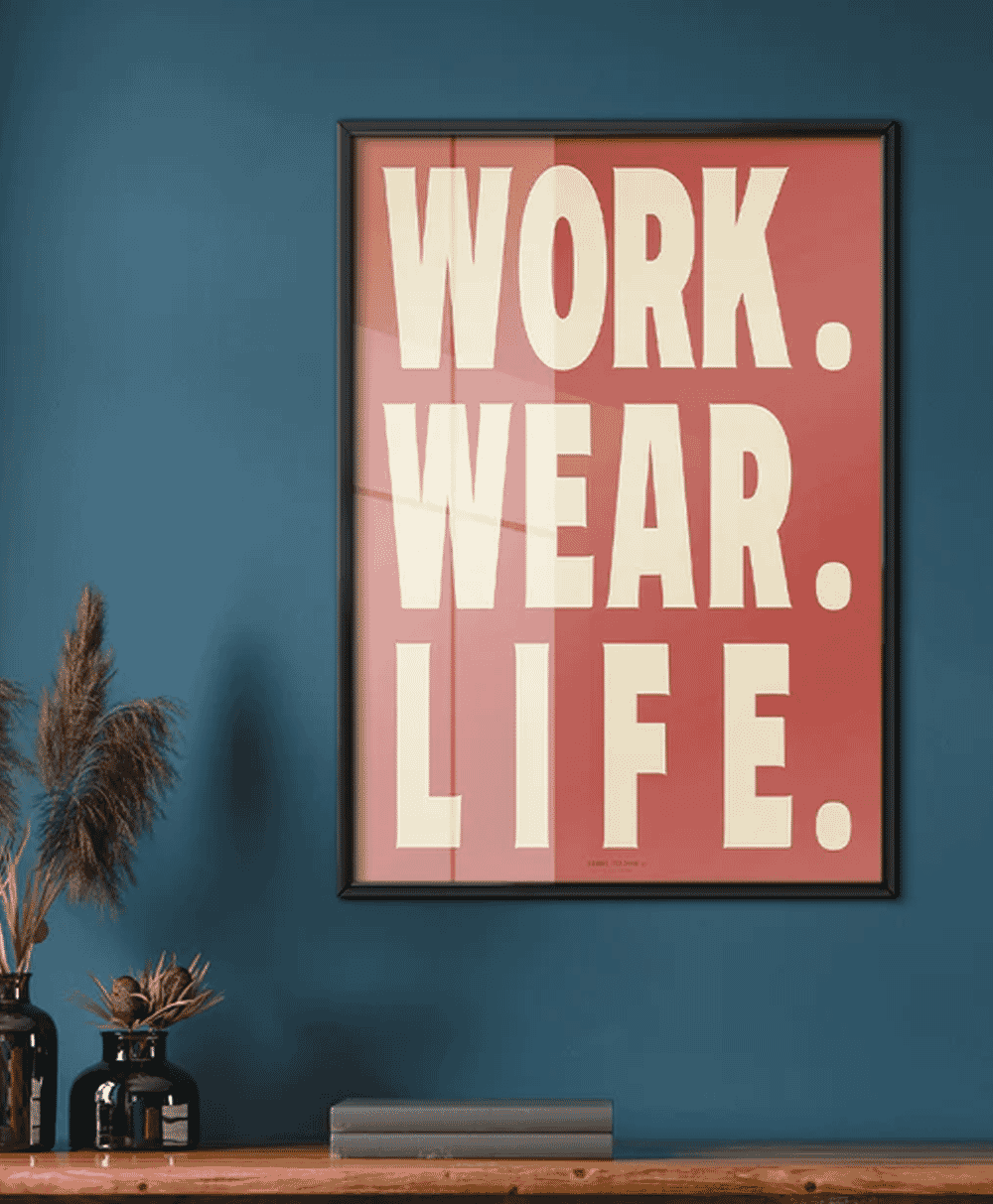 A 'WORK. WEAR. LIFE.' typographic poster on a blue wall styled above a shelf with books and minimalist decor.