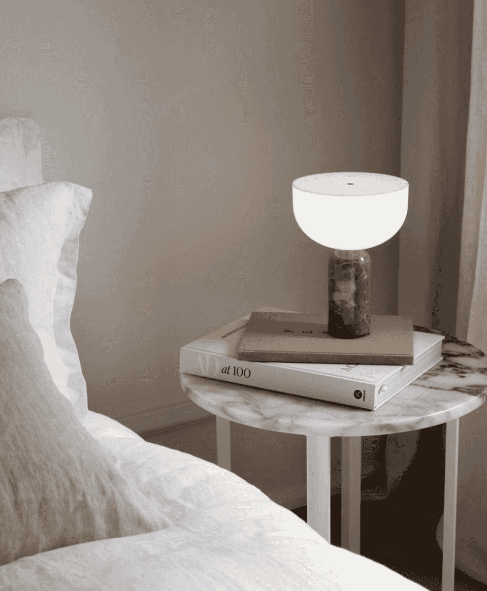 A Kizu Portable Lamp on a marble nightstand in a serene bedroom.