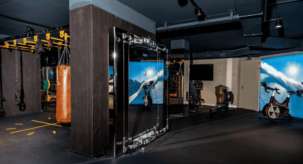 Modern gym interior with exercise bikes and mountain-themed mirrored walls.
