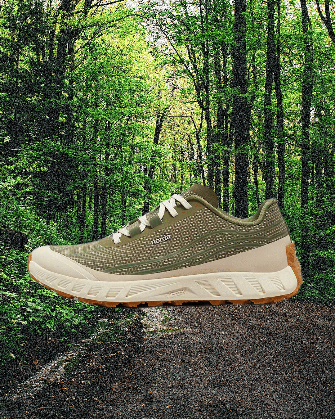 An olive green Norda trail running shoe on a forest dirt path.
