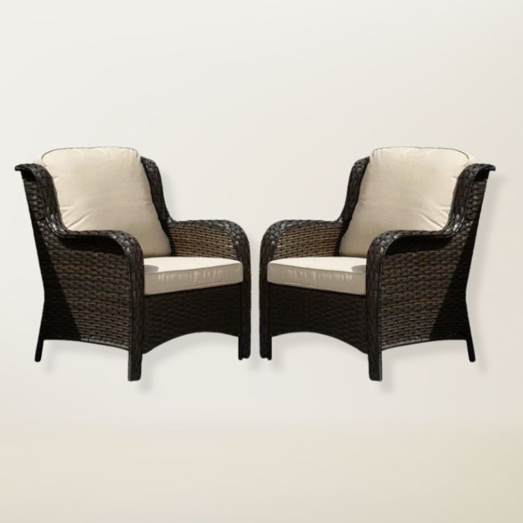 A set of two wicker chairs with white cushions.