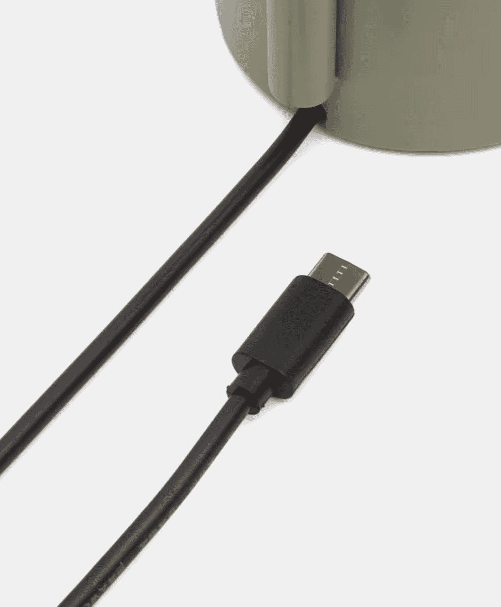 Close-up of a black USB-C cable plugged into a gray portable lamp.