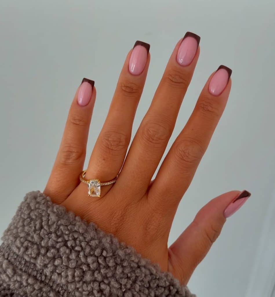 Pink and dark brown French manicure nails with a fuzzy gray sweater.