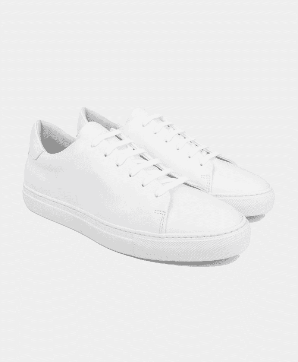 A pair of minimalist white leather sneakers with matching white soles.