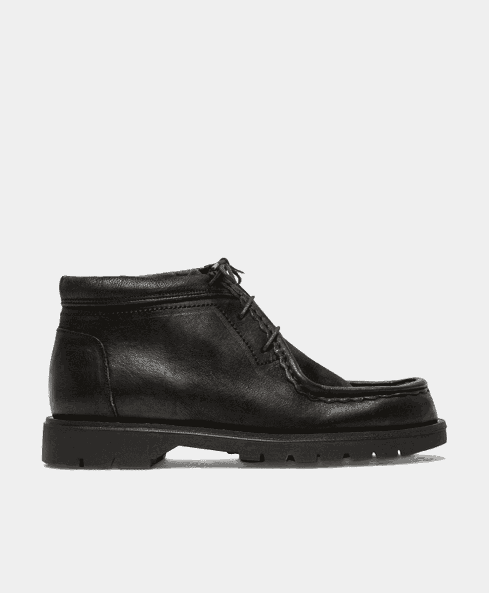 Side-profile of a black leather chukka boot with a chunky rubber sole.