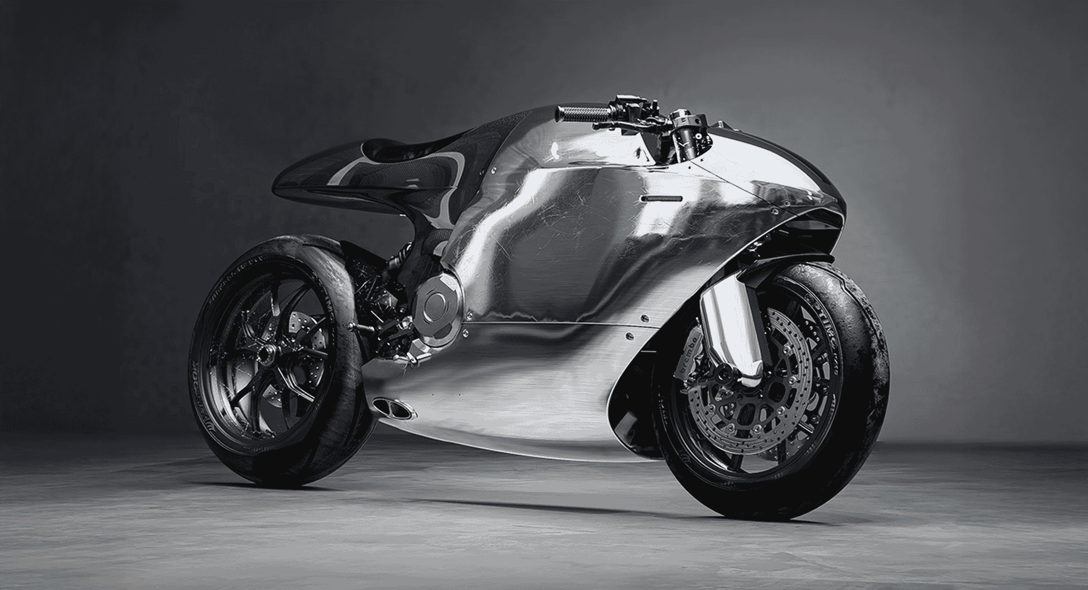 Sleek chrome-finished custom motorcycle with visible carbon fiber accents in a professional studio setting.