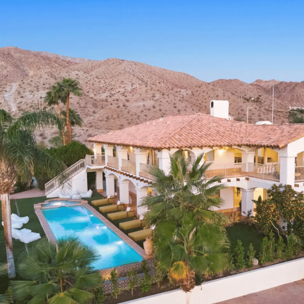 Aerial view of the desert villa featuring terracotta roofs, a pool, and surrounding palm trees.