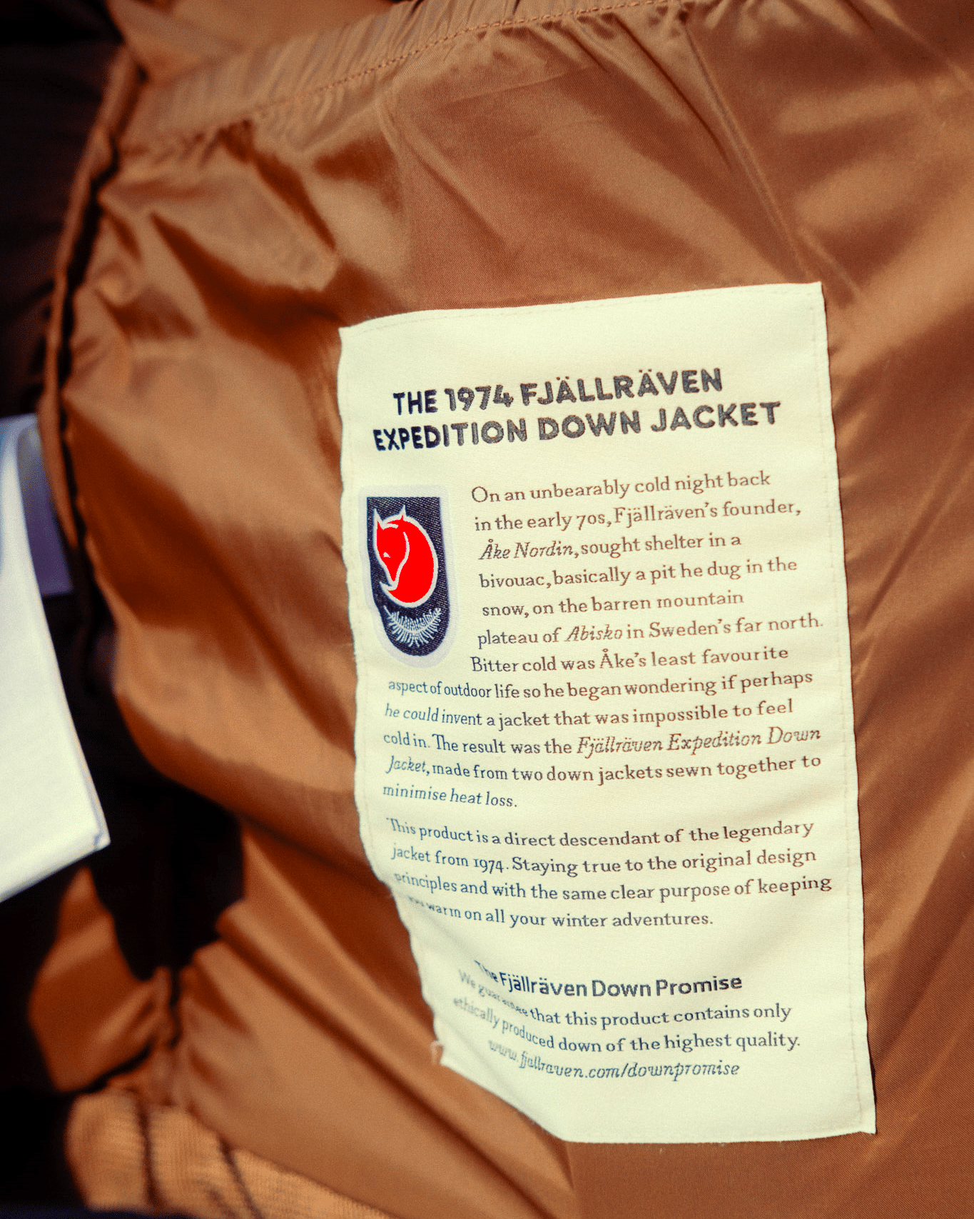 Close-up of the brown Fjällräven Expedition Down Jacket label showing the 1974 heritage text.