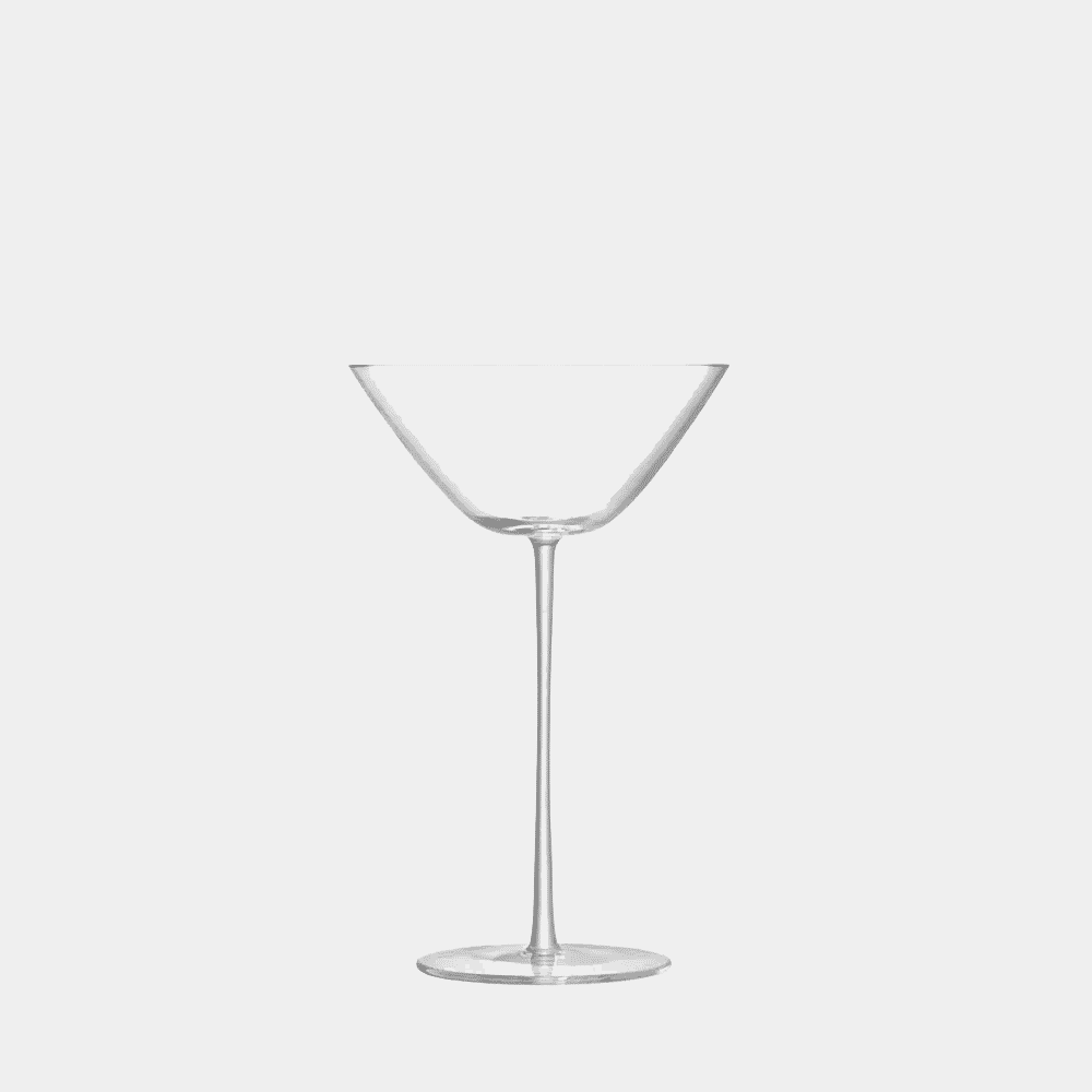 A minimalist clear crystal martini glass with a long slender stem on a white background.