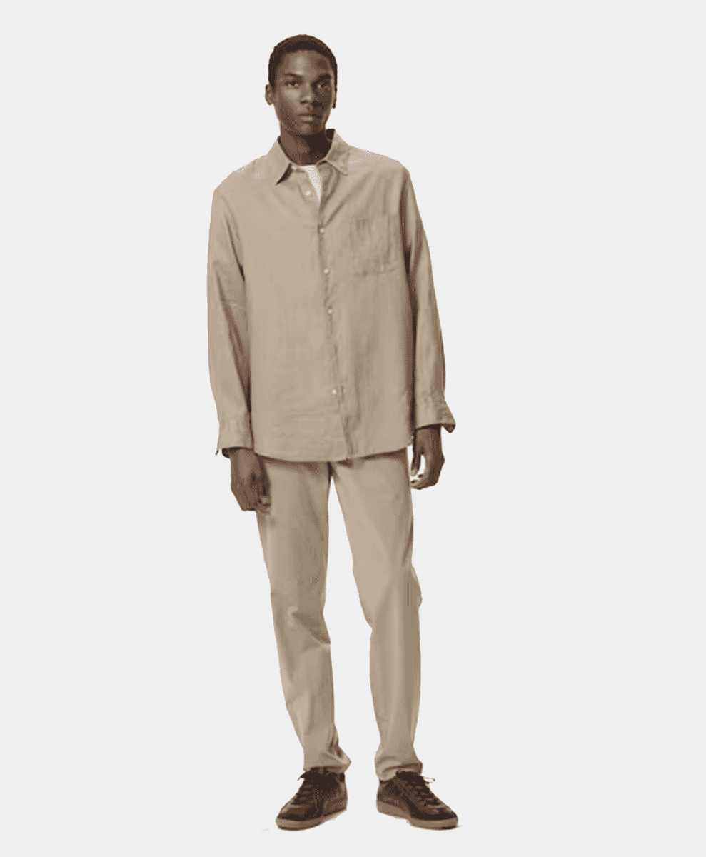 Man in a beige oversized button-up shirt and matching trousers.