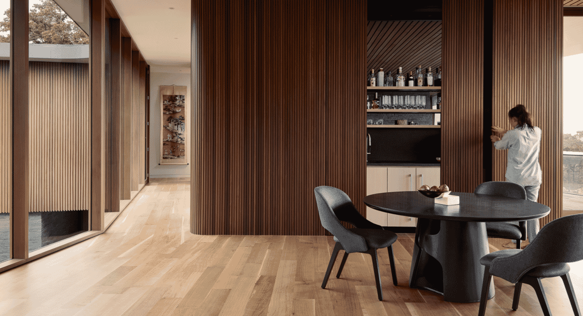 A woman interacting with a sliding wooden panel in a minimalist modern interior.