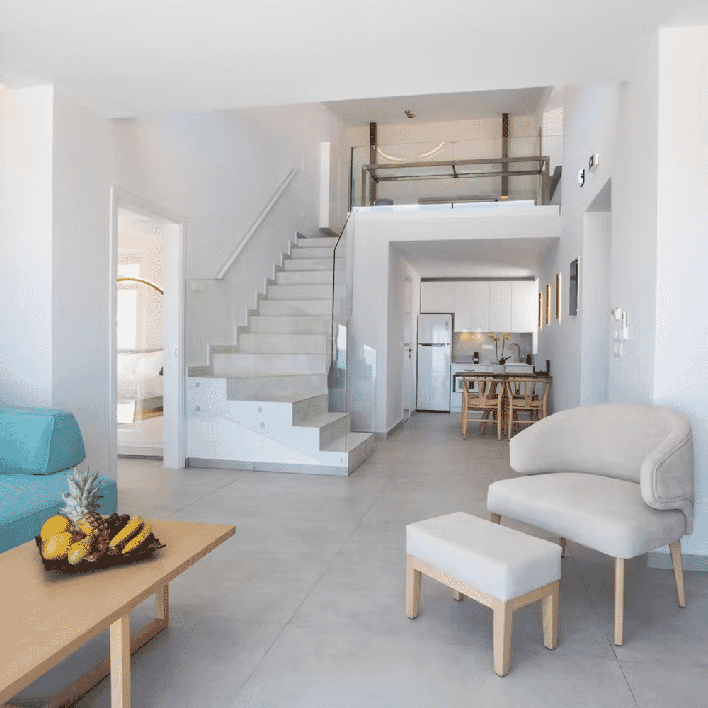 Bright, minimalist open-plan living area featuring white marble stairs and a turquoise sofa.