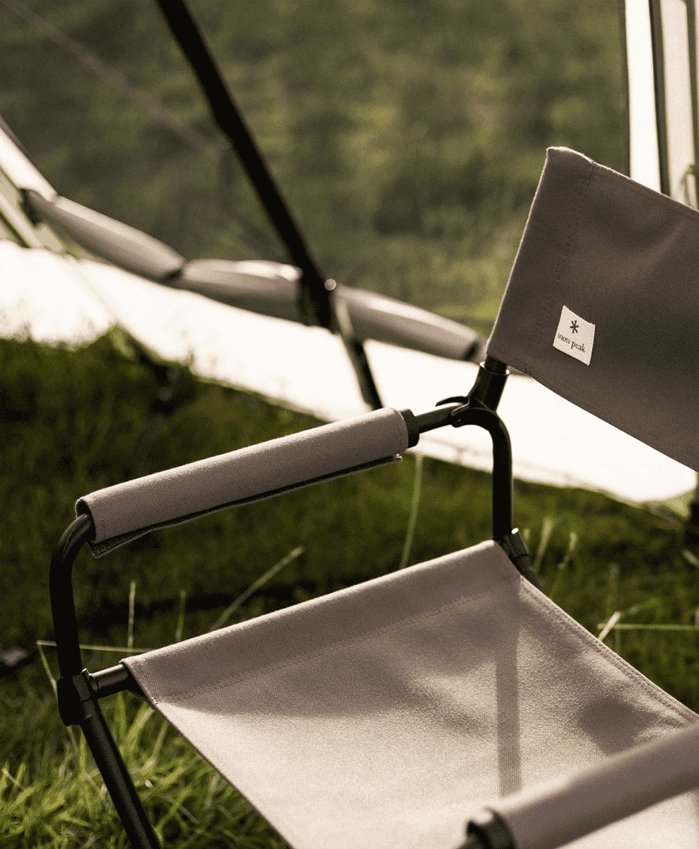 Snow Peak folding camp chair set outdoors on grass.