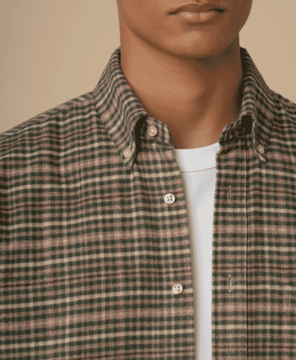 Close-up of a man wearing a brown and green checkered button-down shirt.