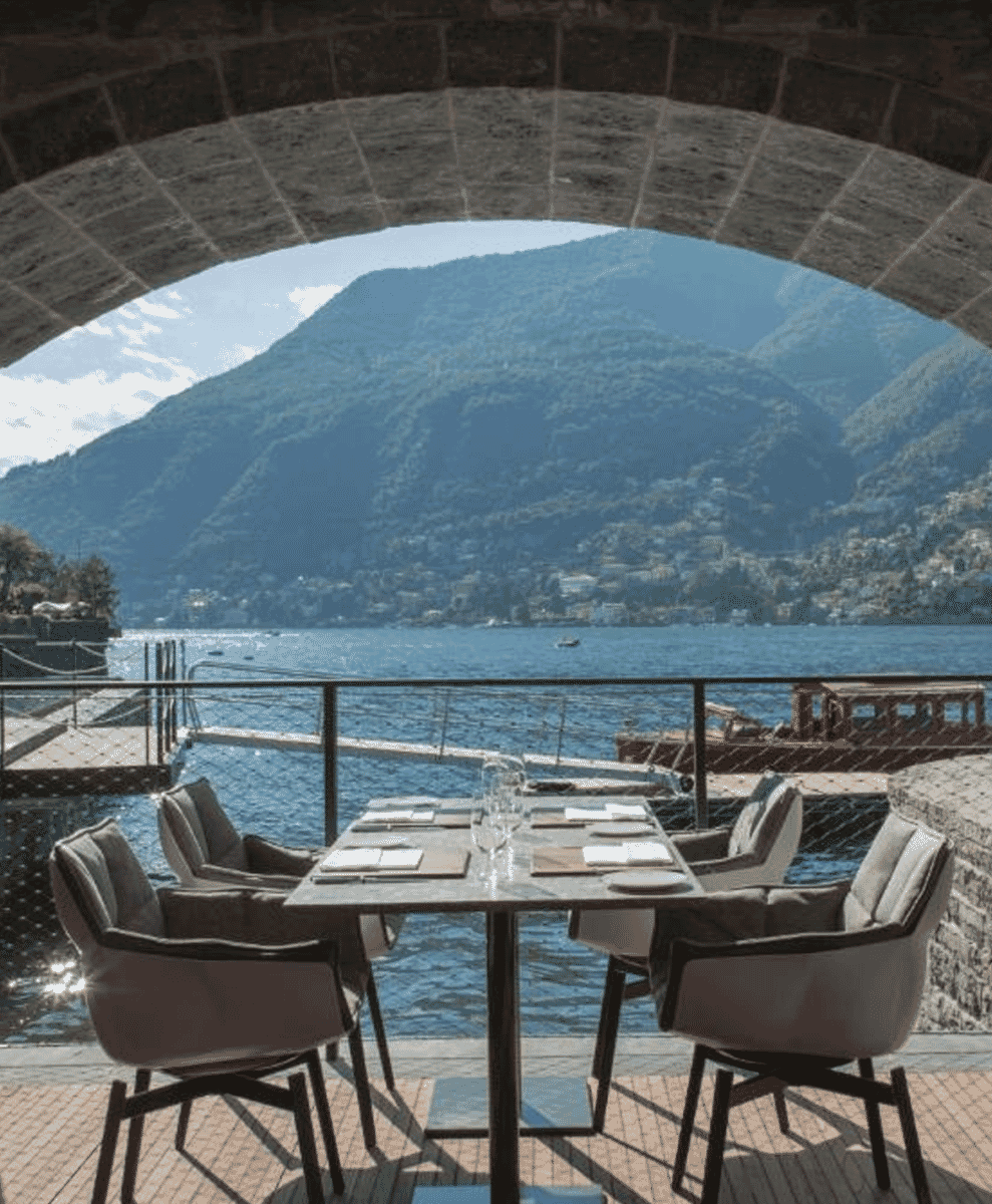 Outdoor Michelin-starred dining setup under a historic stone arch at Il Sereno overlooking Lake Como.