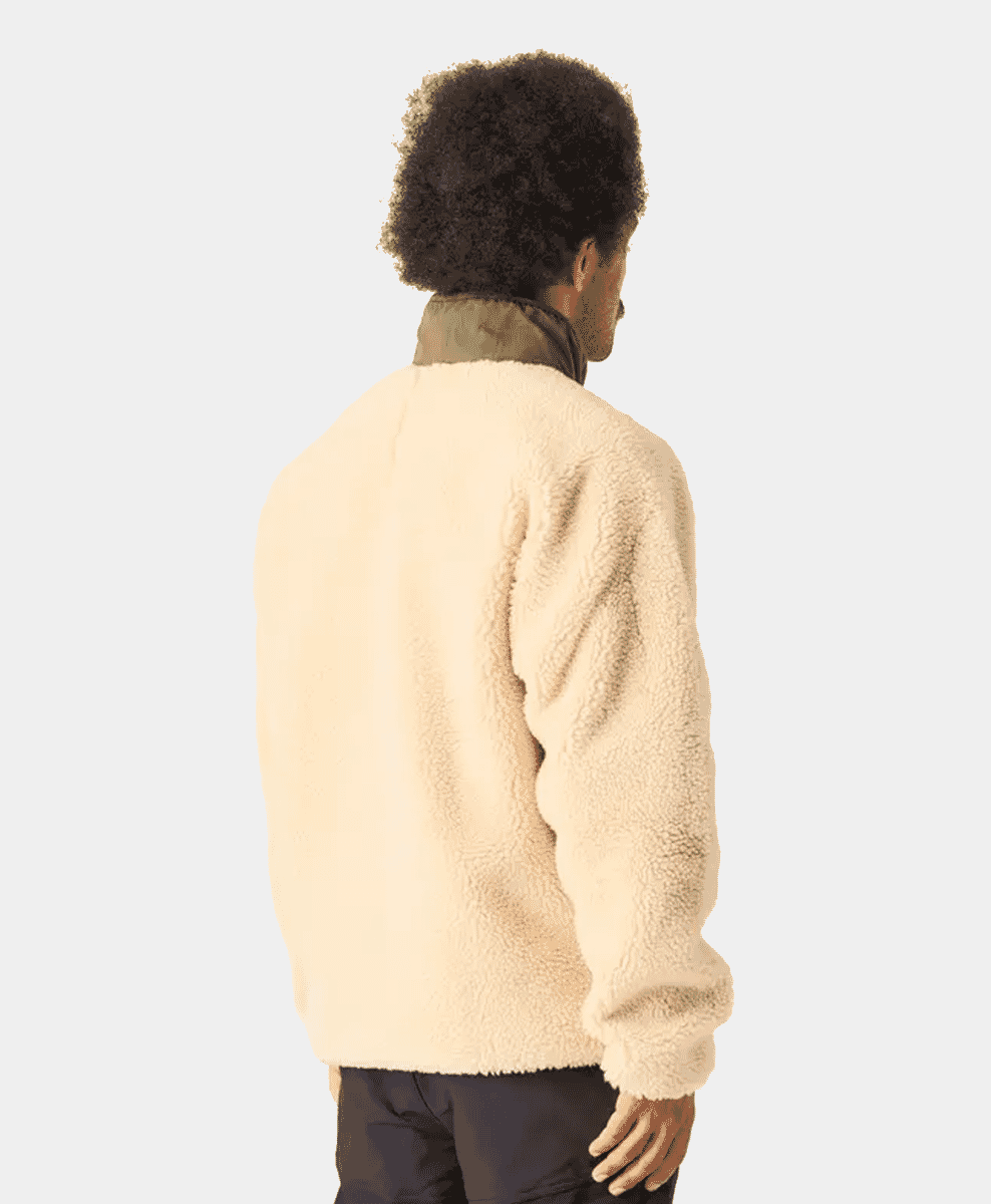 Back view of a man wearing a cream-colored sherpa jacket with an olive green collar.