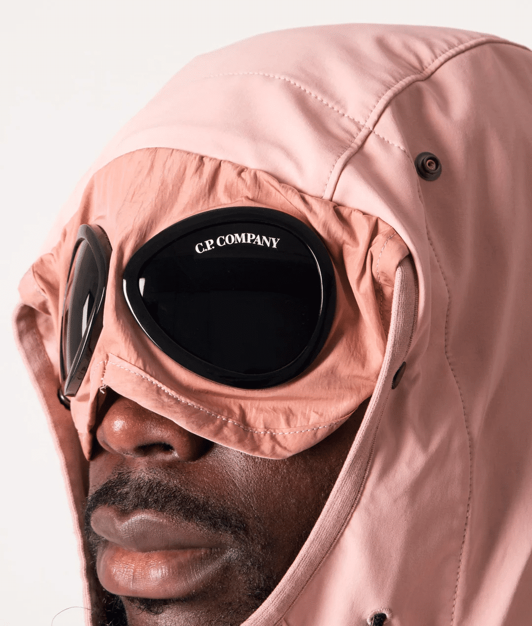 Detail view of the C.P. Company goggle jacket in a soft pink shade.
