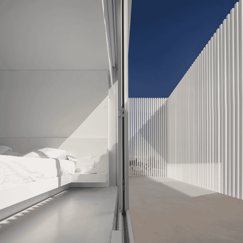 Minimalist white bedroom interior with clean lines and views of the exterior architectural slats.