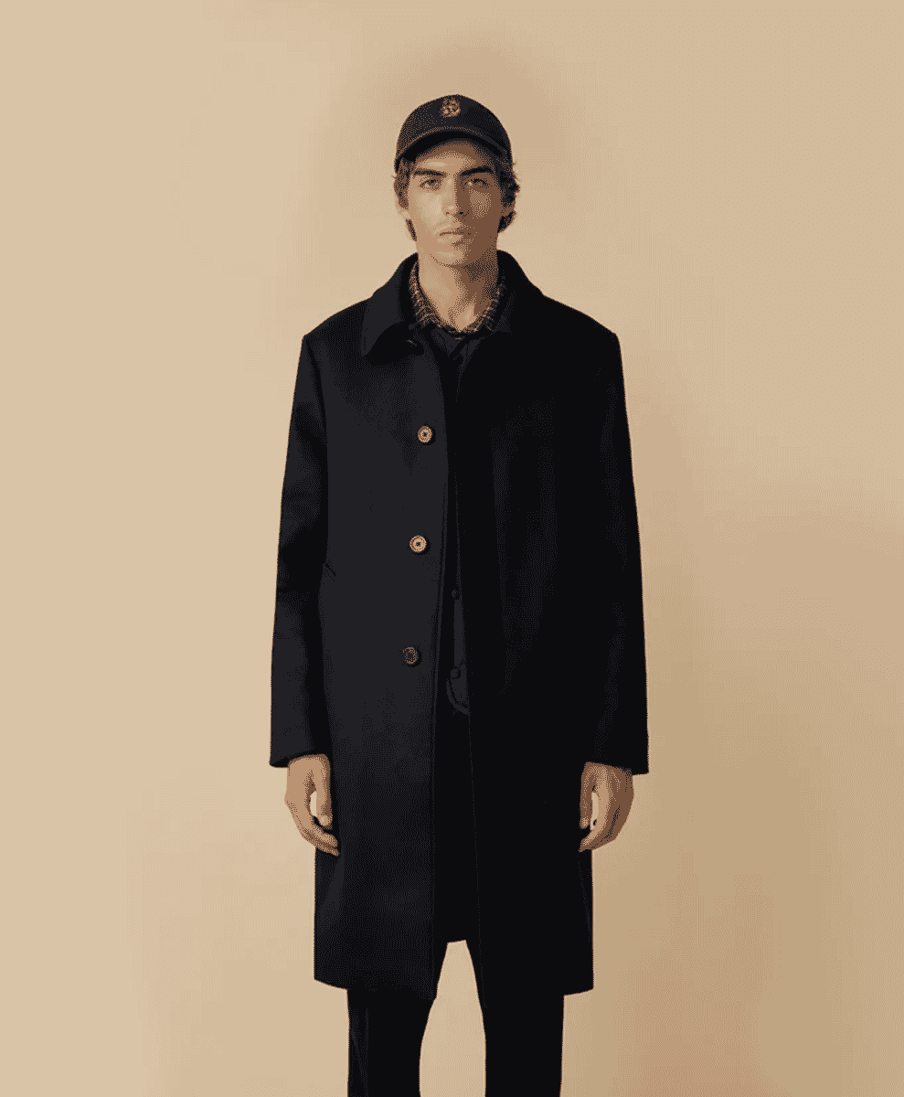 A male model in a navy wool coat with wooden toggles and a patterned shirt.