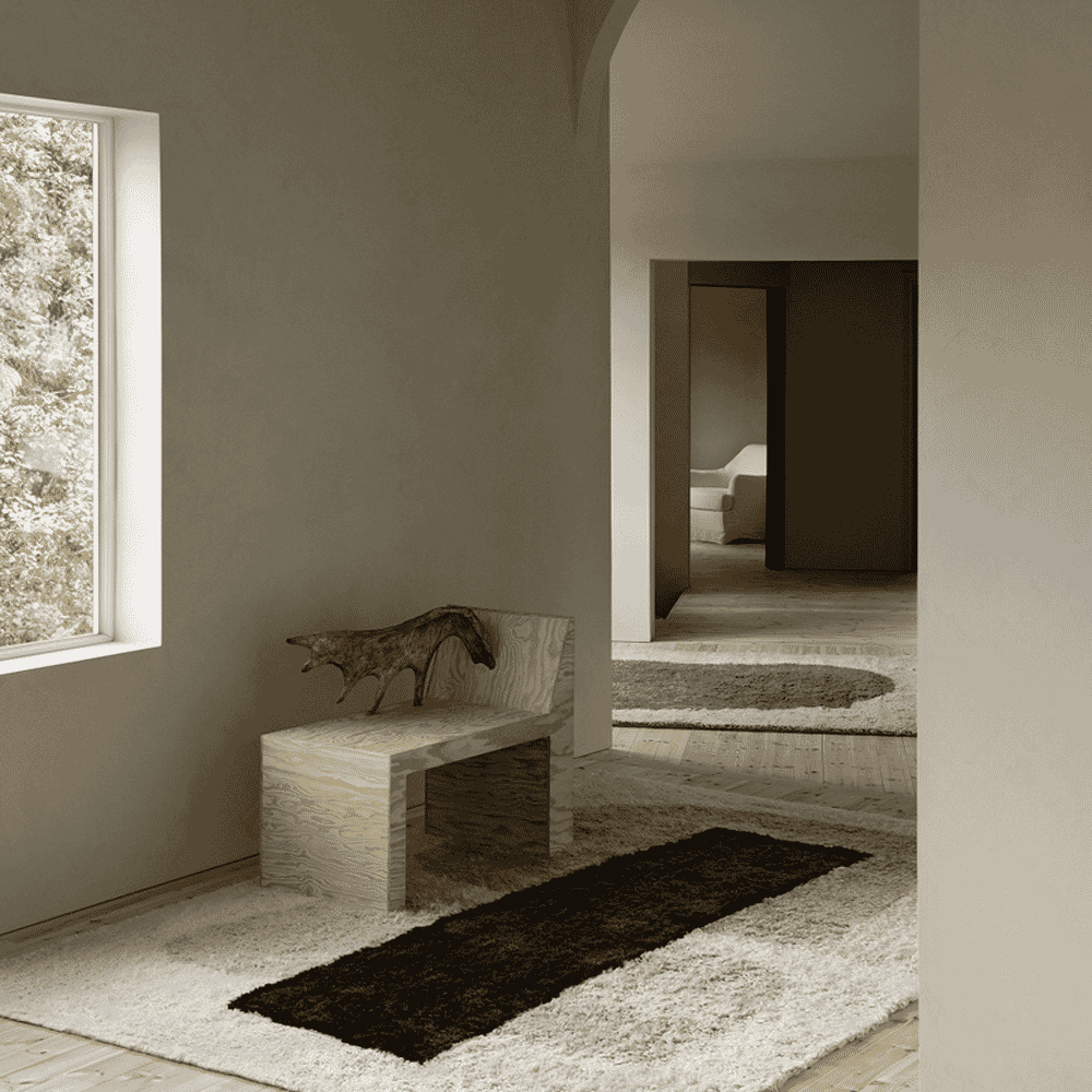 Minimalist interior with a wooden bench, a fox sculpture, and layered rugs under soft natural window light.