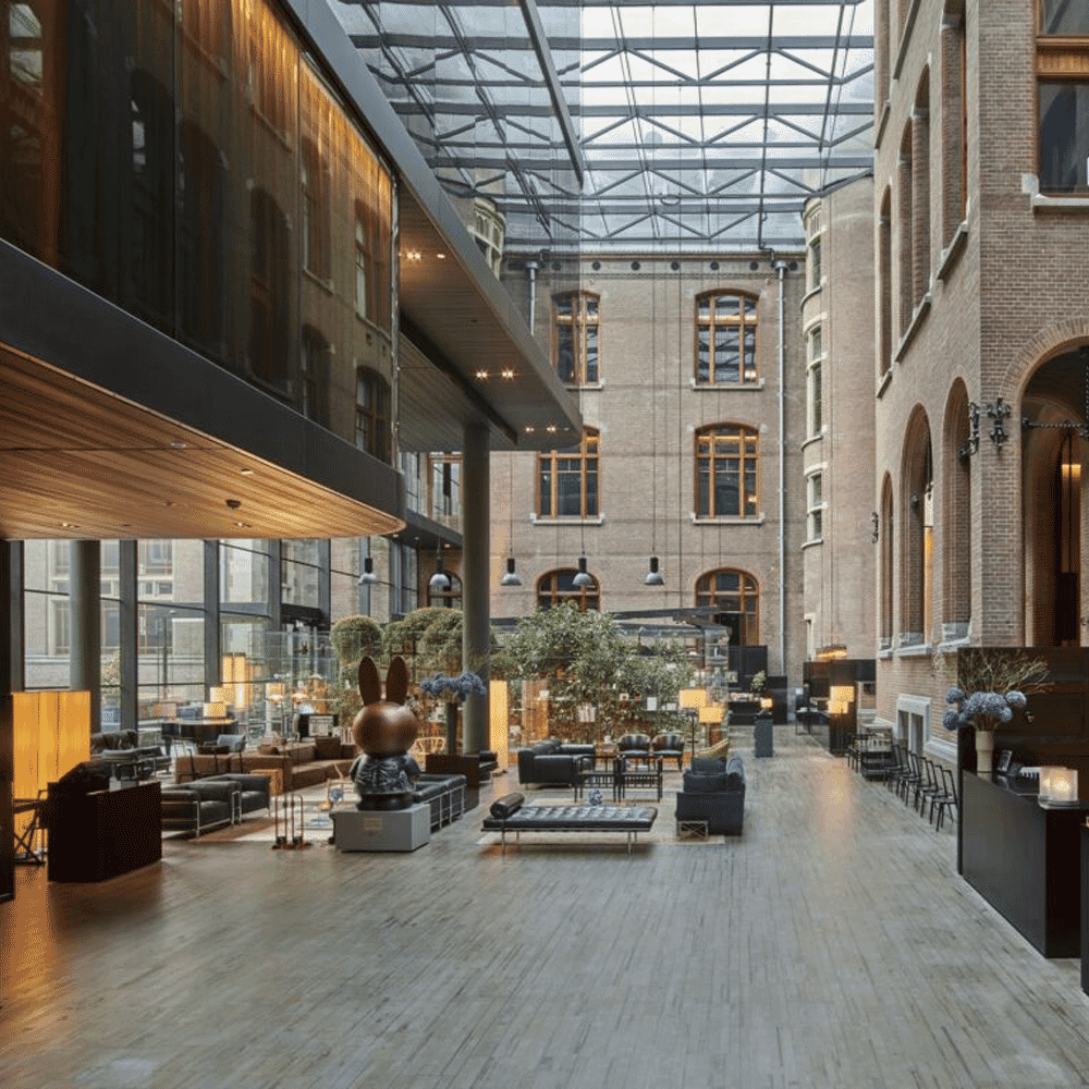 Modern indoor atrium with a soaring glass ceiling and contemporary furnishings.