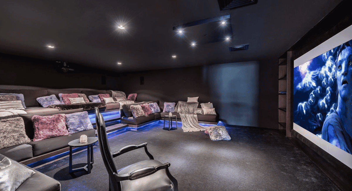 Luxurious home theater with tiered plush seating and ambient blue lighting.