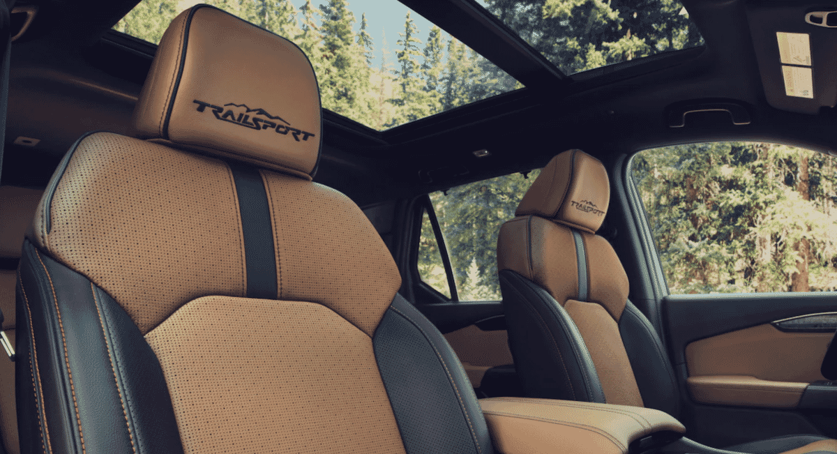 Interior of a luxury SUV with leather seats featuring 'TRAILSPORT' embroidery and a sunroof view.