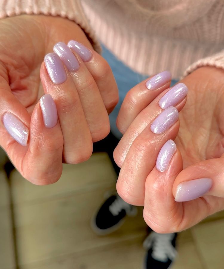 Purple iridescent glazed shimmer nails reflecting soft light.