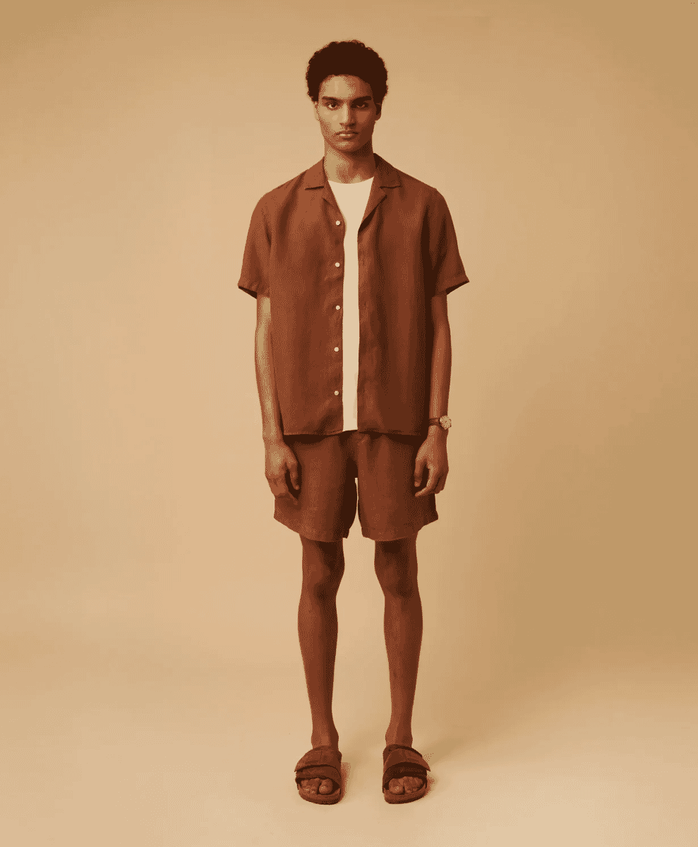 A man modeling a brown camp-collar linen shirt worn over a white t-shirt.