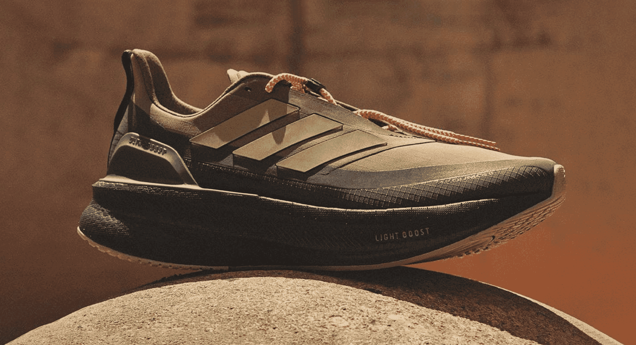 Side view of the black and beige Adidas UltraBOOST 5 highlighting the Light Boost technology.