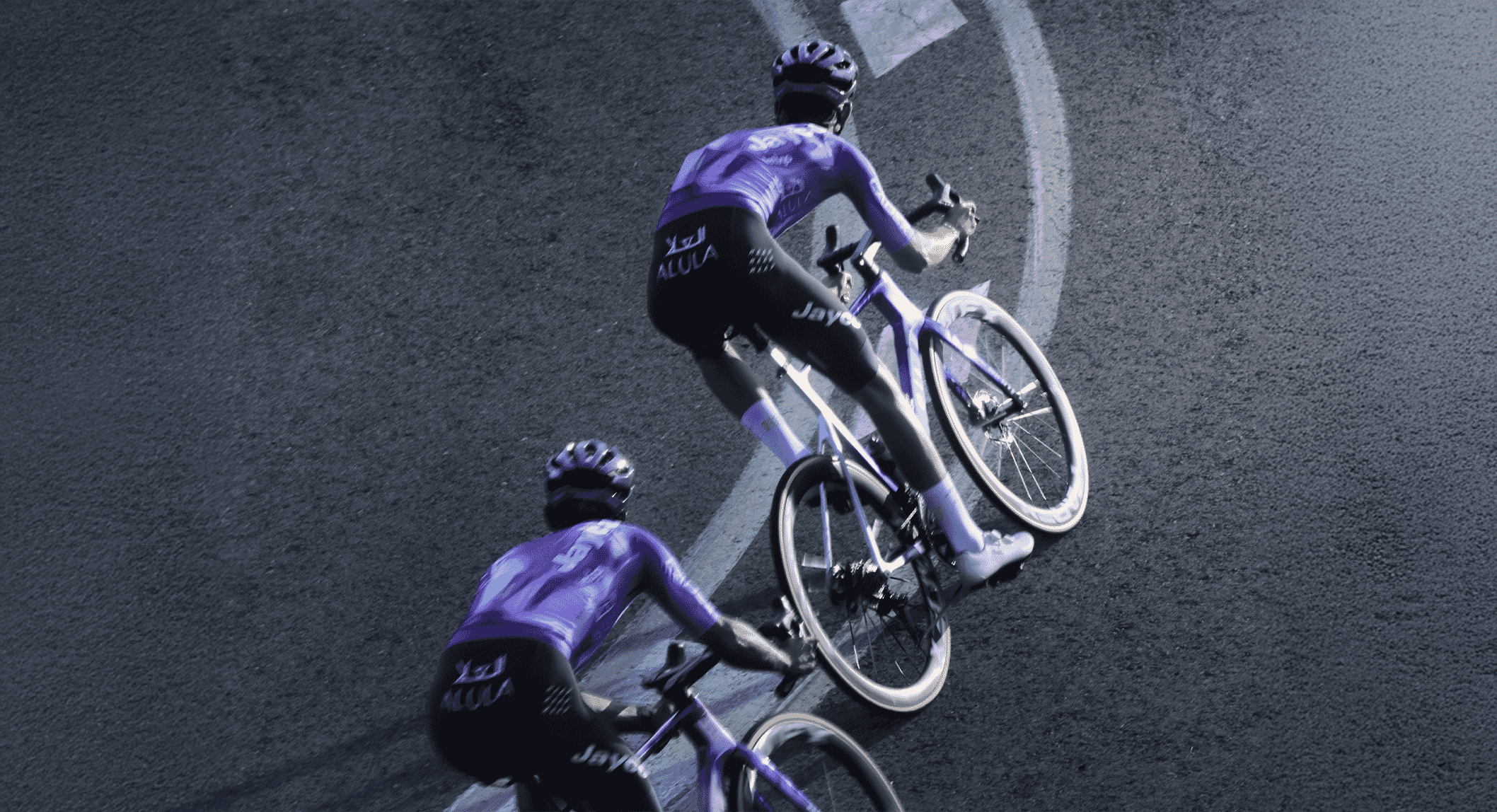 Two cyclists in full aerodynamic purple team jerseys and gear riding on a track.