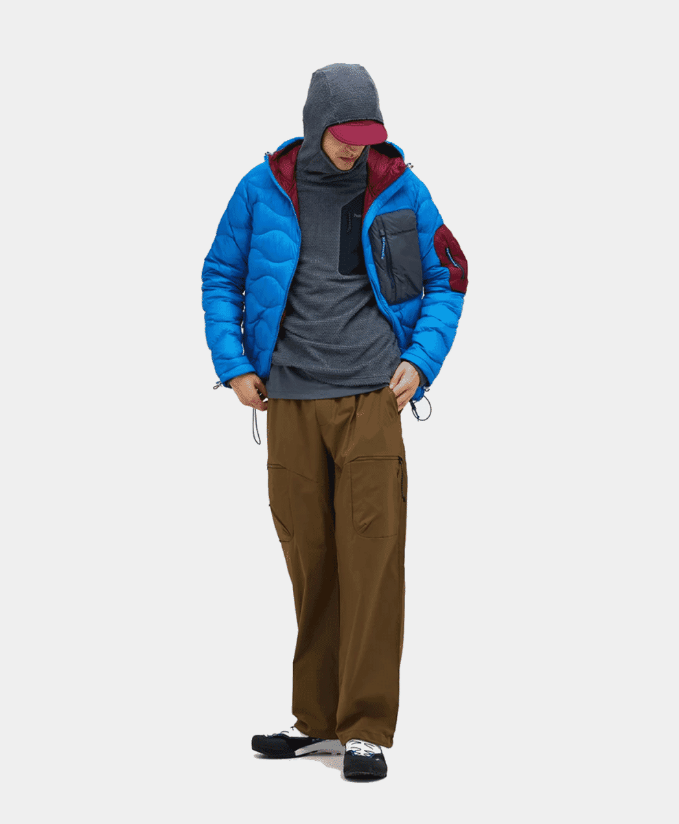 A man wearing a blue puffer jacket with brown cargo pants against a white background.