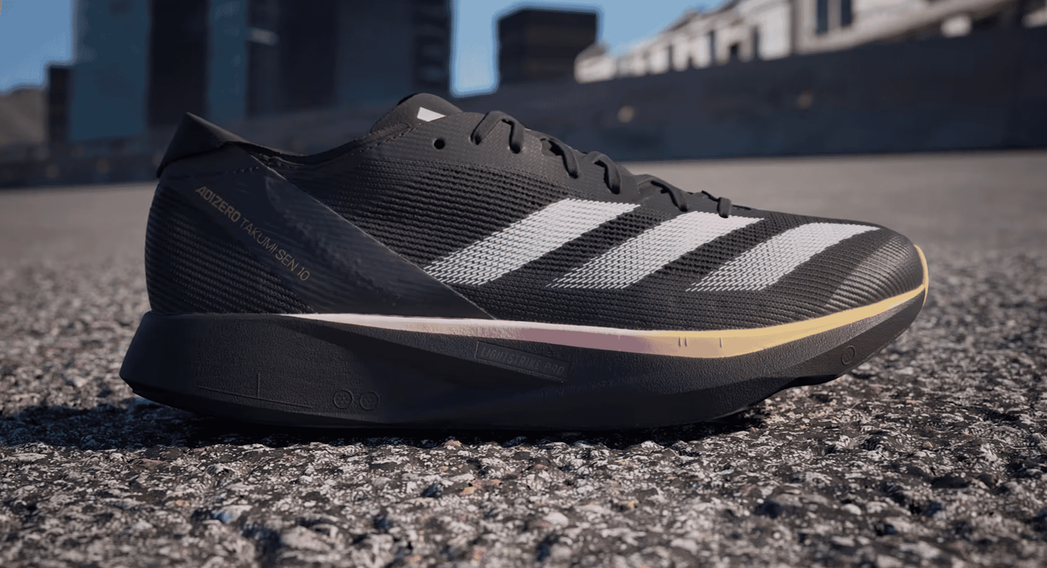 Black Adidas Adizero Takumi Sen 10 on asphalt, highlighting its lightweight design.
