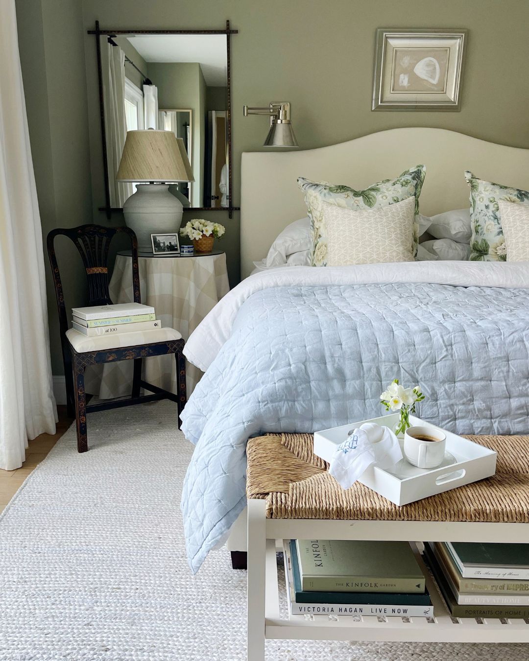 A bedroom with sage green walls and neutral bedding.