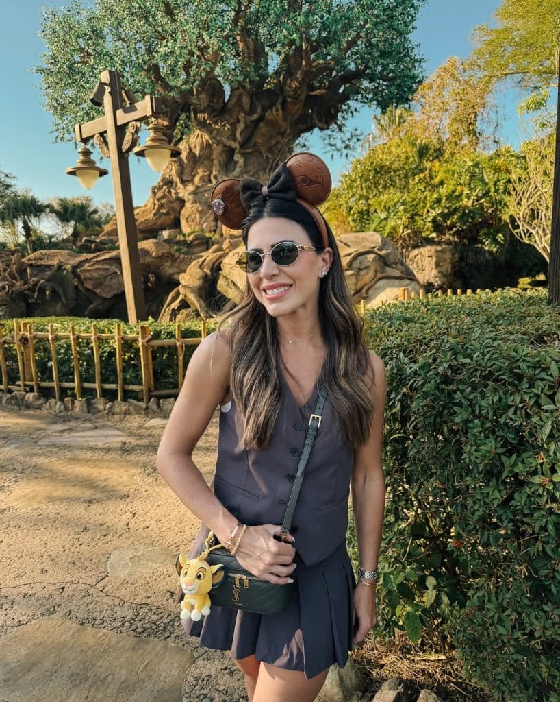 A woman in a dark gray sleeveless dress and Mickey ears near the Tree of Life.