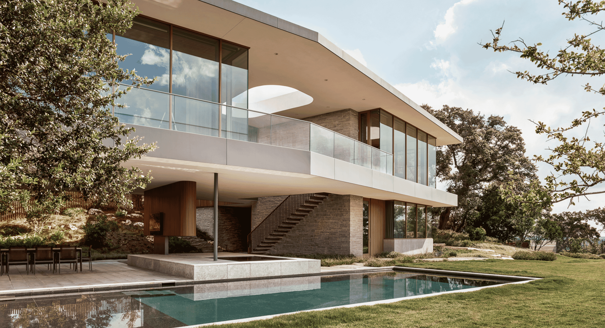 Modern house with glass balconies and a swimming pool surrounded by greenery.