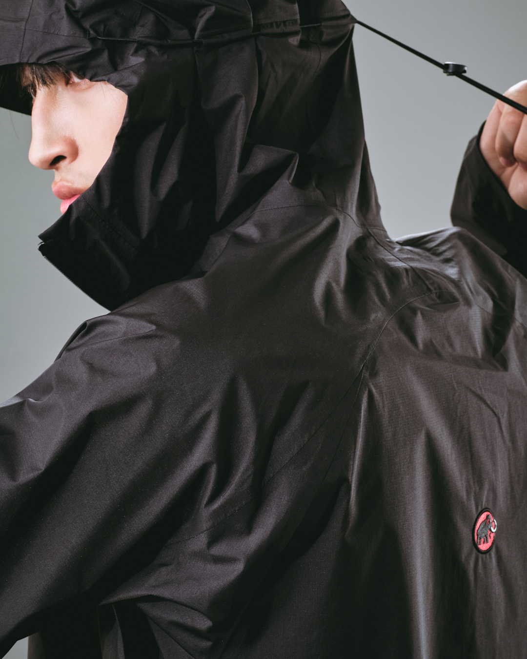 Street style shot featuring a layered shell jacket over a hoodie and cargo pants.