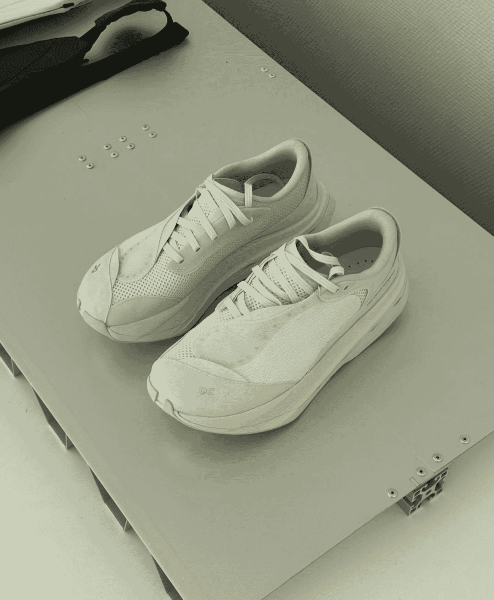 White ON running sneakers displayed on an industrial metallic surface with hardware.