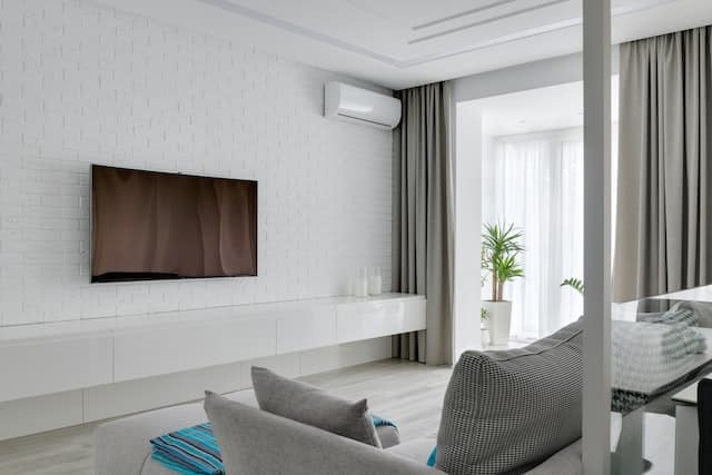 Modern minimalist living room featuring a gray sofa and floor-length curtains on large windows.