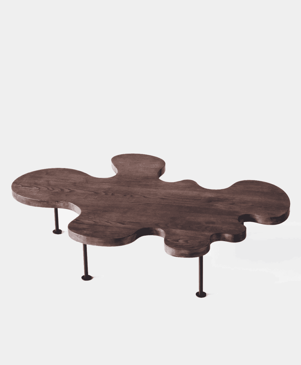 A modern sculptural coffee table with an organic puzzle-piece-shaped wooden top and metal legs.