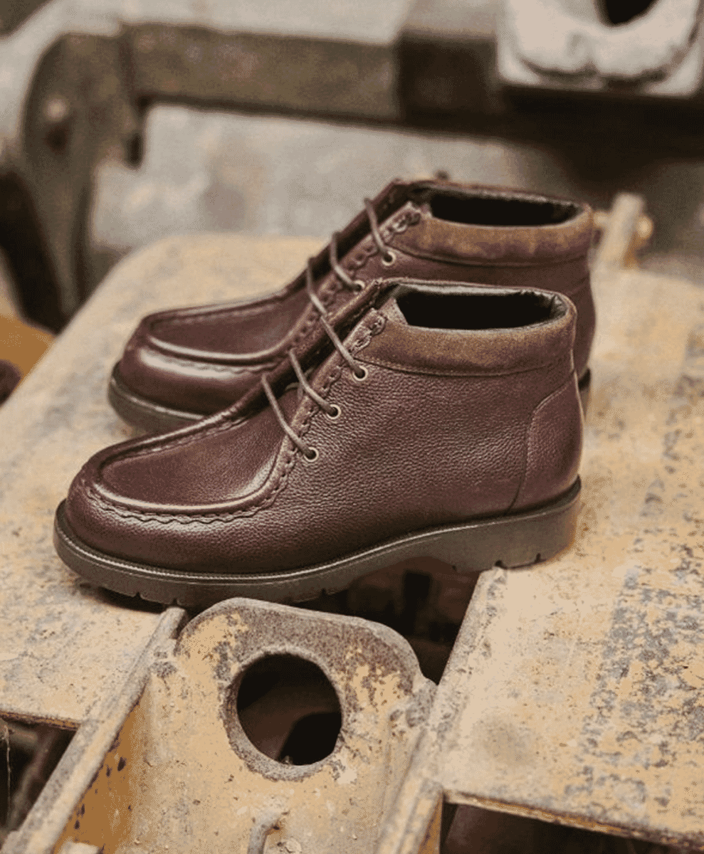 Brown pebbled-leather chukka boots resting on an industrial metal surface.