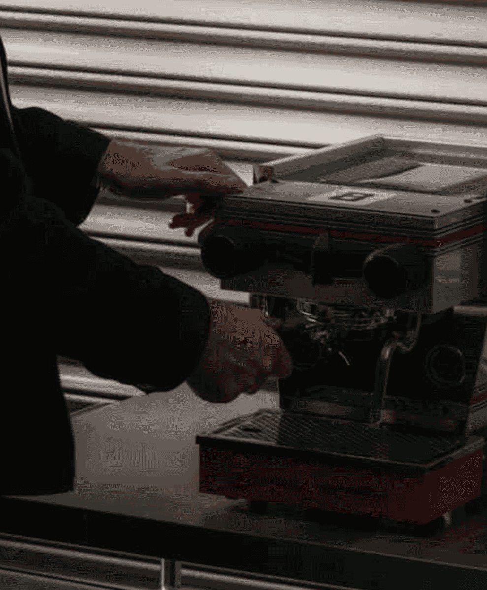 A person operating the professional espresso machine in a focused setting.